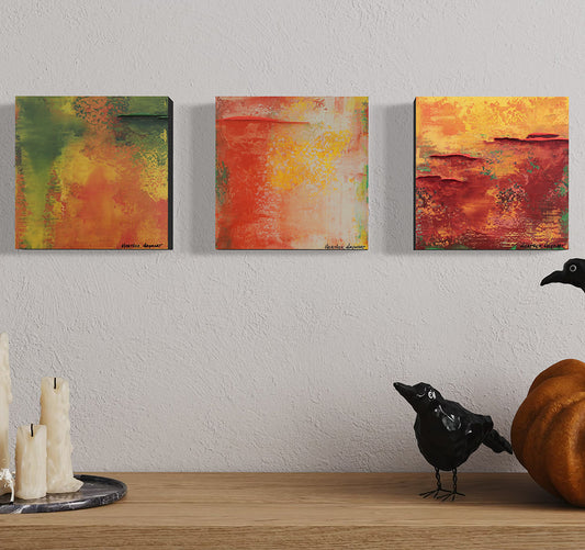 Three abstract paintings on a wall with decorative items on a shelf below.