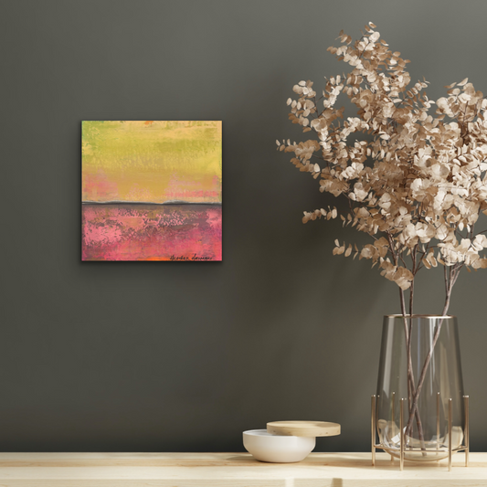 Artwork on the wall over a shelf with a vase of dried flowers
