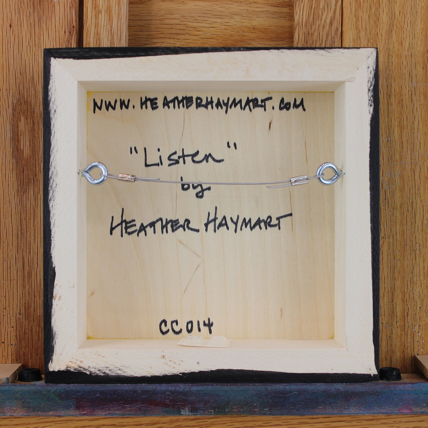 Back view of framed artwork with a wire, signed by Heather Haymart.
