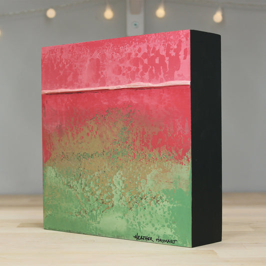 Artistic box with pink and green abstract design on a wooden surface