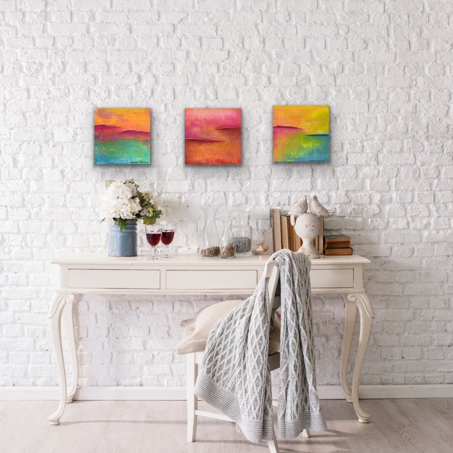 Three colorful acrylic paintings on brick wall over desk