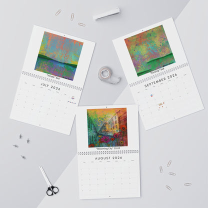 Three calendar pages showing colorful artwork on a light gray surface with stationery items.