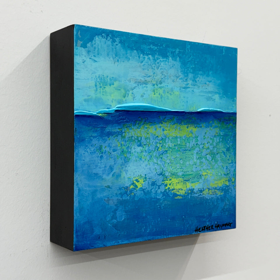 side view of abstract painting of a blue and green ocean scene on a white wall