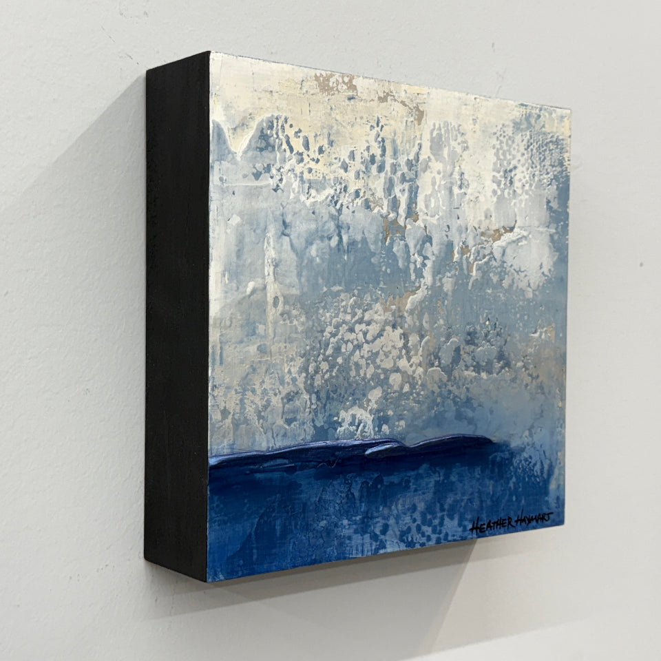Side view of abstract textured art with blue and beige tones on a white wall