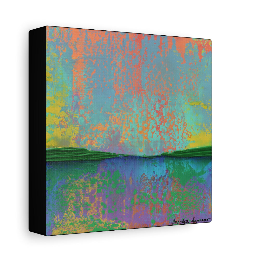 A square abstract landscape-style wall art print or canvas shown at a slight angle, with a black side edge and a white background. The artwork contains blended areas of turquoise, coral, yellow, green, blue, purple, and pink, with darker green landforms near the bottom.