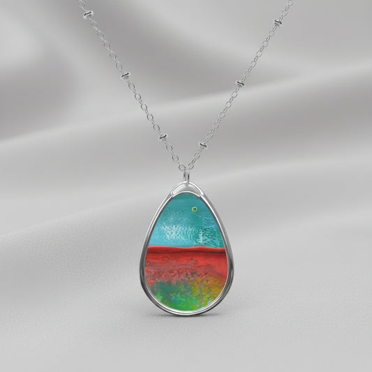 A teardrop-shaped art pendant necklace with a colorful abstract design, featuring a brass pendant on a silver chain.