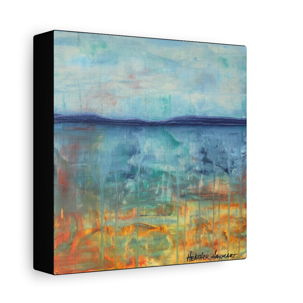 Abstract landscape canvas wall art featuring a blue and teal sky over a reflective body of water with orange and yellow tones near the horizon, shown as a three-quarter perspective view with a black side edge on a white background.