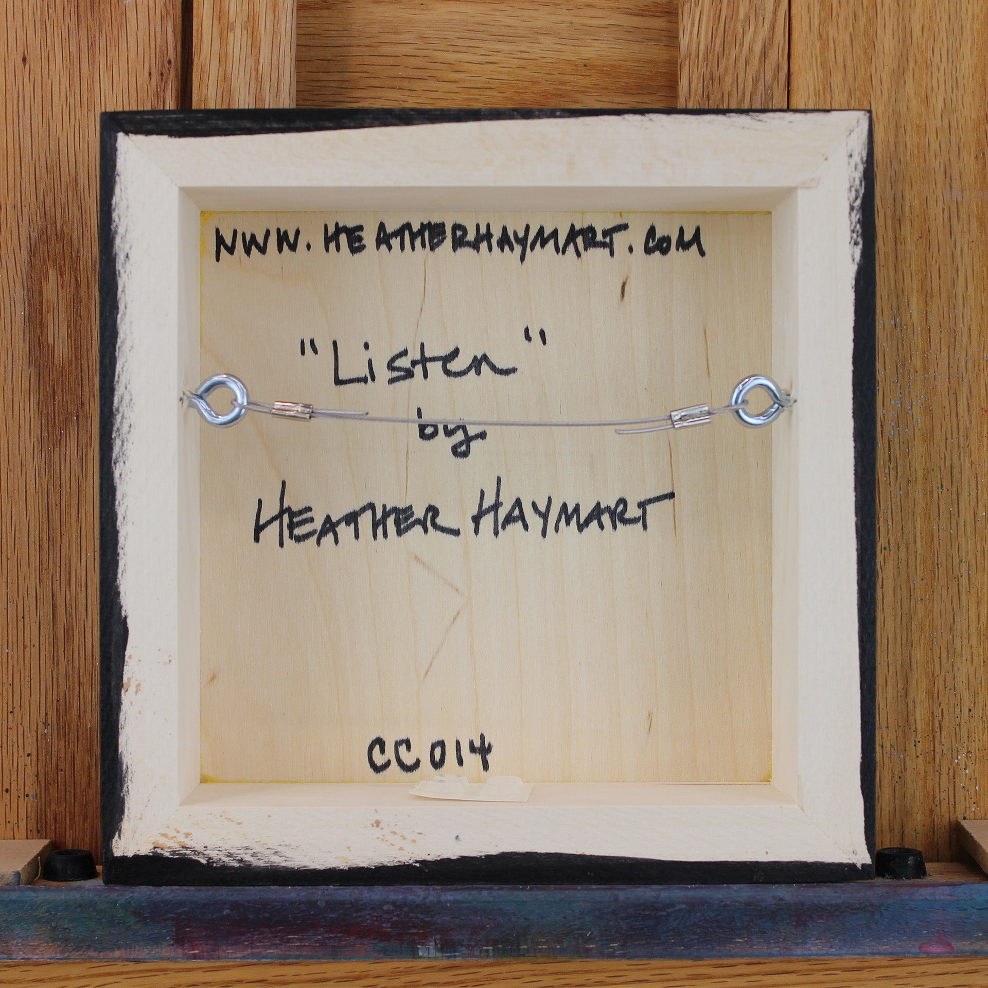 Back view of framed artwork with a wire, signed by Heather Haymart.