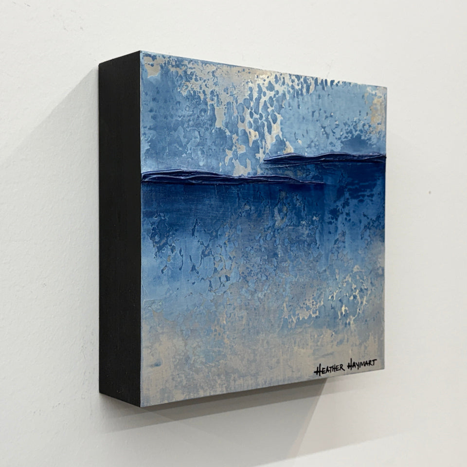 Side view of abstract texture art with blue and gray tones on a white wall