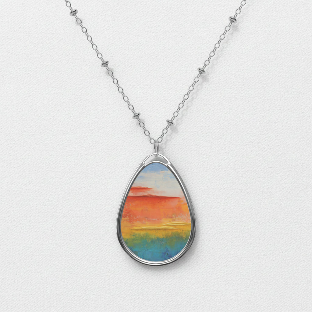 A teardrop-shaped art pendant necklace with a multicolored image, displayed on a chain.