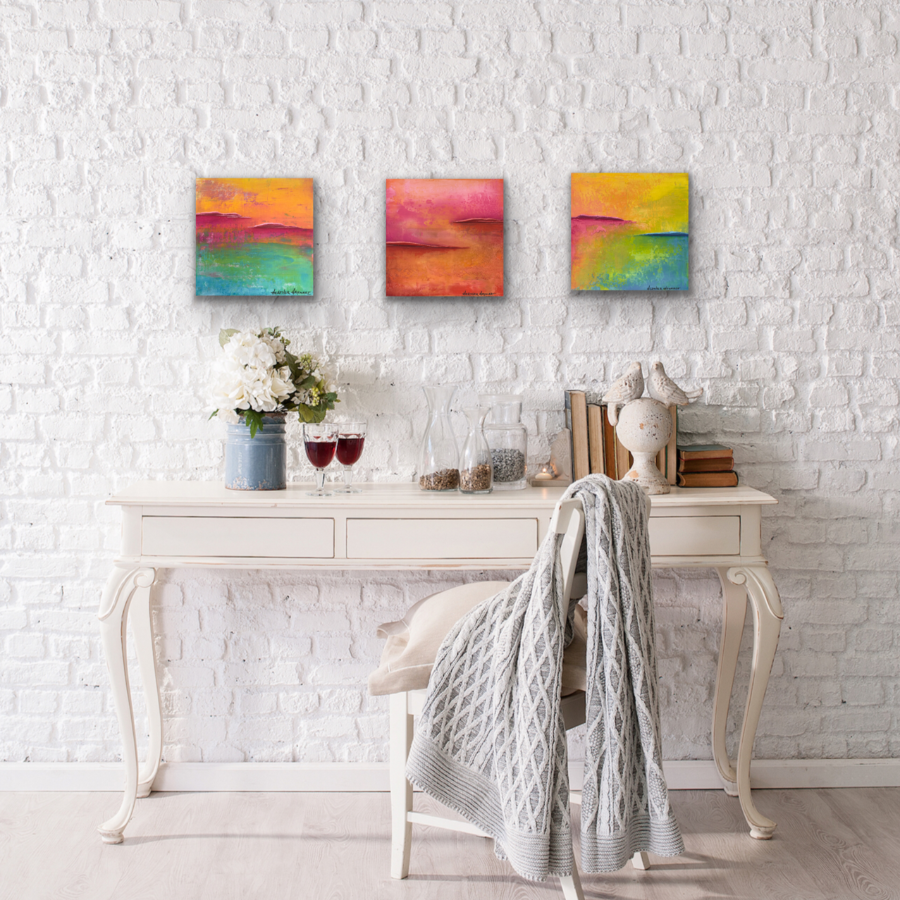 An abstract art grouping of three; Sparkling, Something Lovely and Daydreamy on a brick wall over a desk.