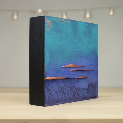 Decorative box with a blue and turquoise design on a wooden surface