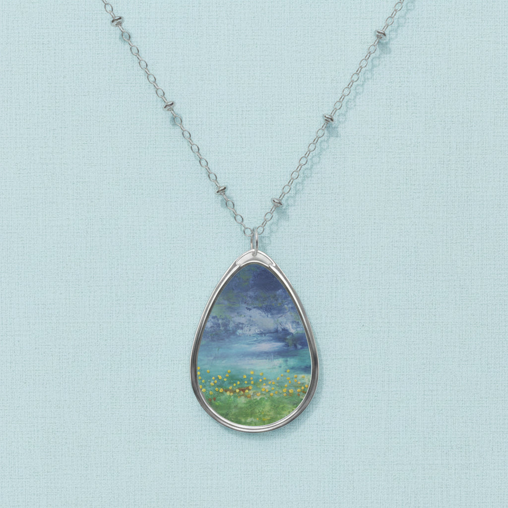 A teardrop-shaped art pendant necklace with a white and blue color scheme, featuring an artistic depiction of a natural scene.