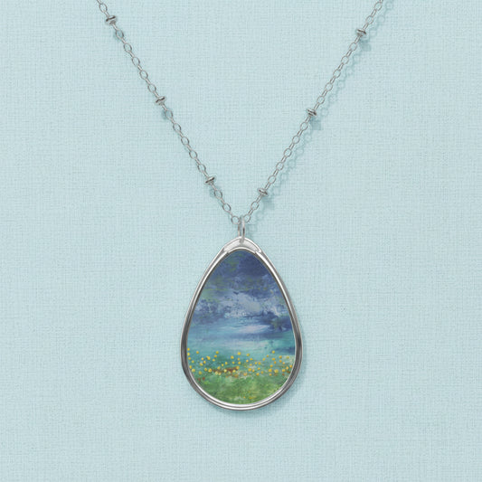 A teardrop-shaped art pendant necklace with a white and blue color scheme, featuring an artistic depiction of a natural scene.