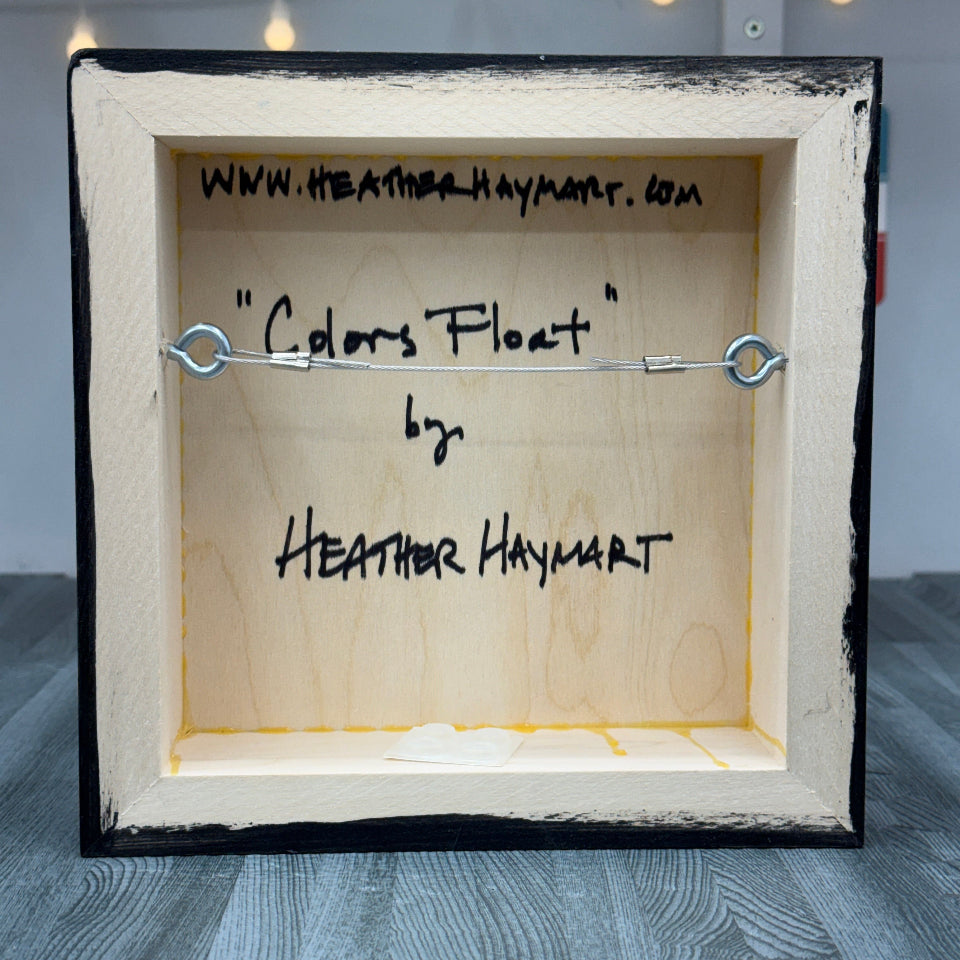 Back of a framed artwork with 'Colors Float' by Heather Haymart text.