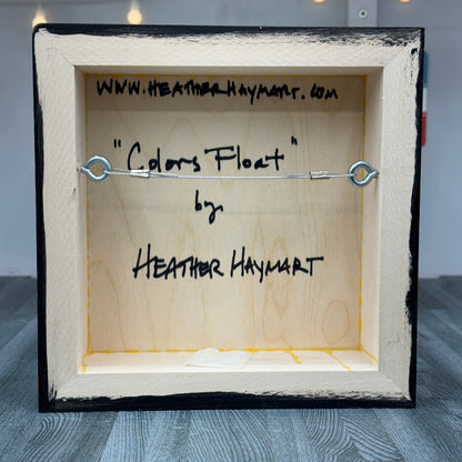 Back of a framed artwork with 'Colors Float' by Heather Haymart text.